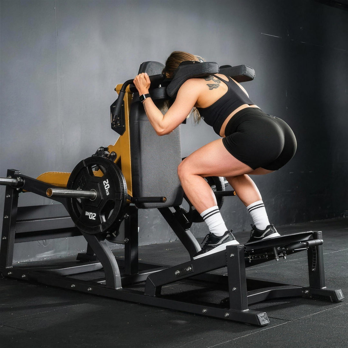 Athlète en squat sur la machine fessiers UltraFitness chargée d'un disque de 20 kg